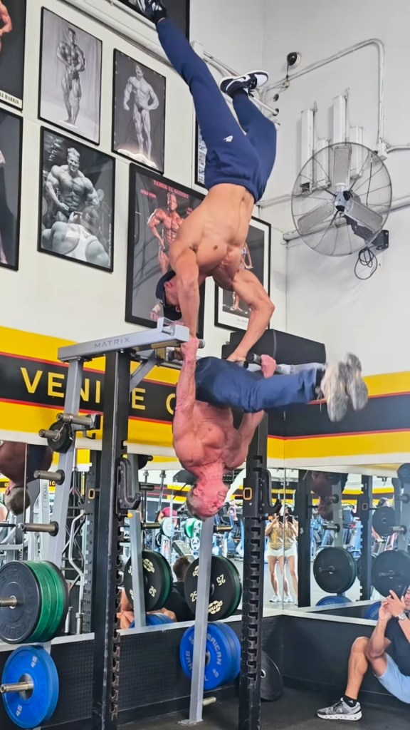 Two men performing a workout using a dip station in a gym.