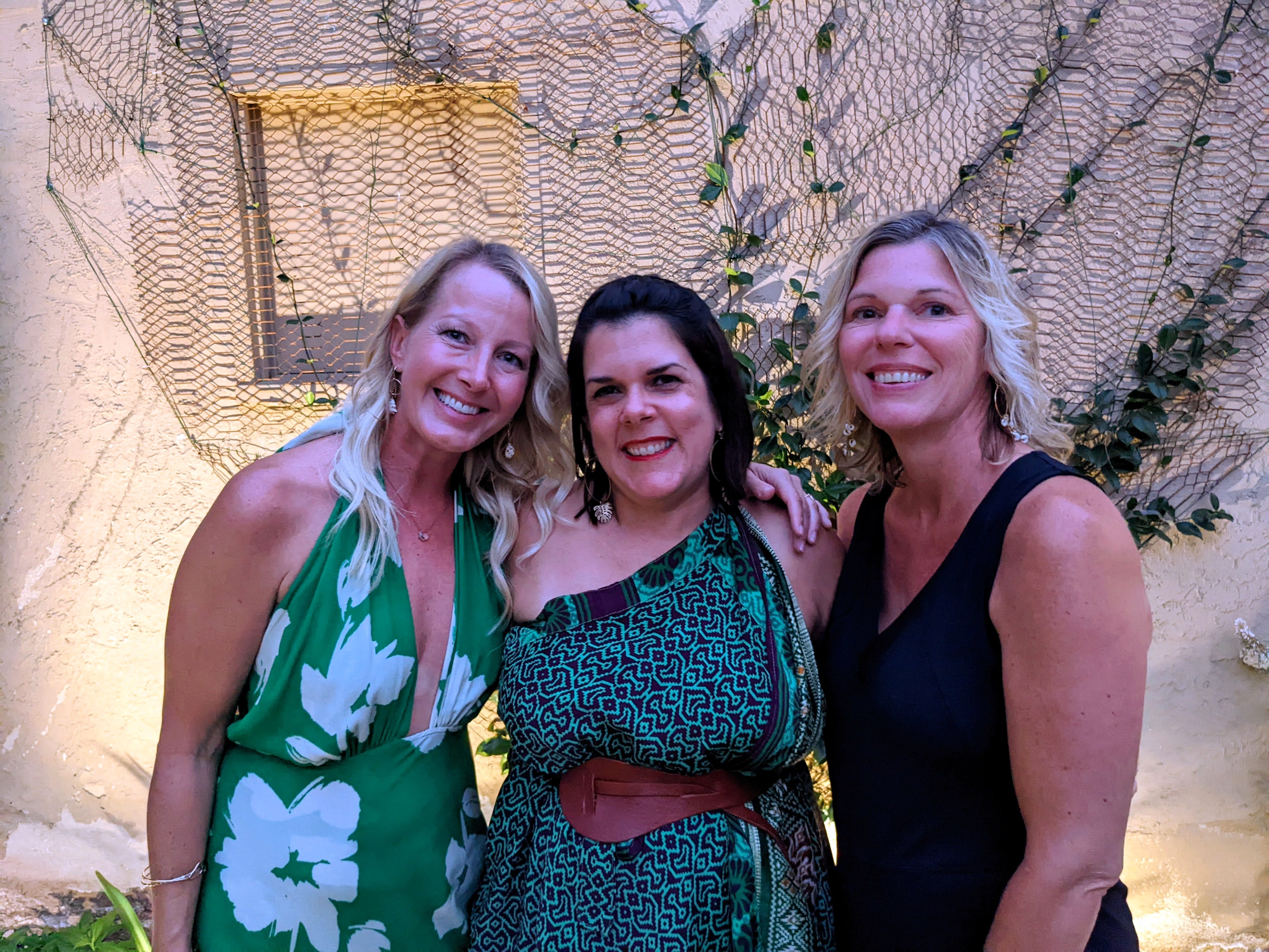 Three women smiling for the camera in fancy dresses.