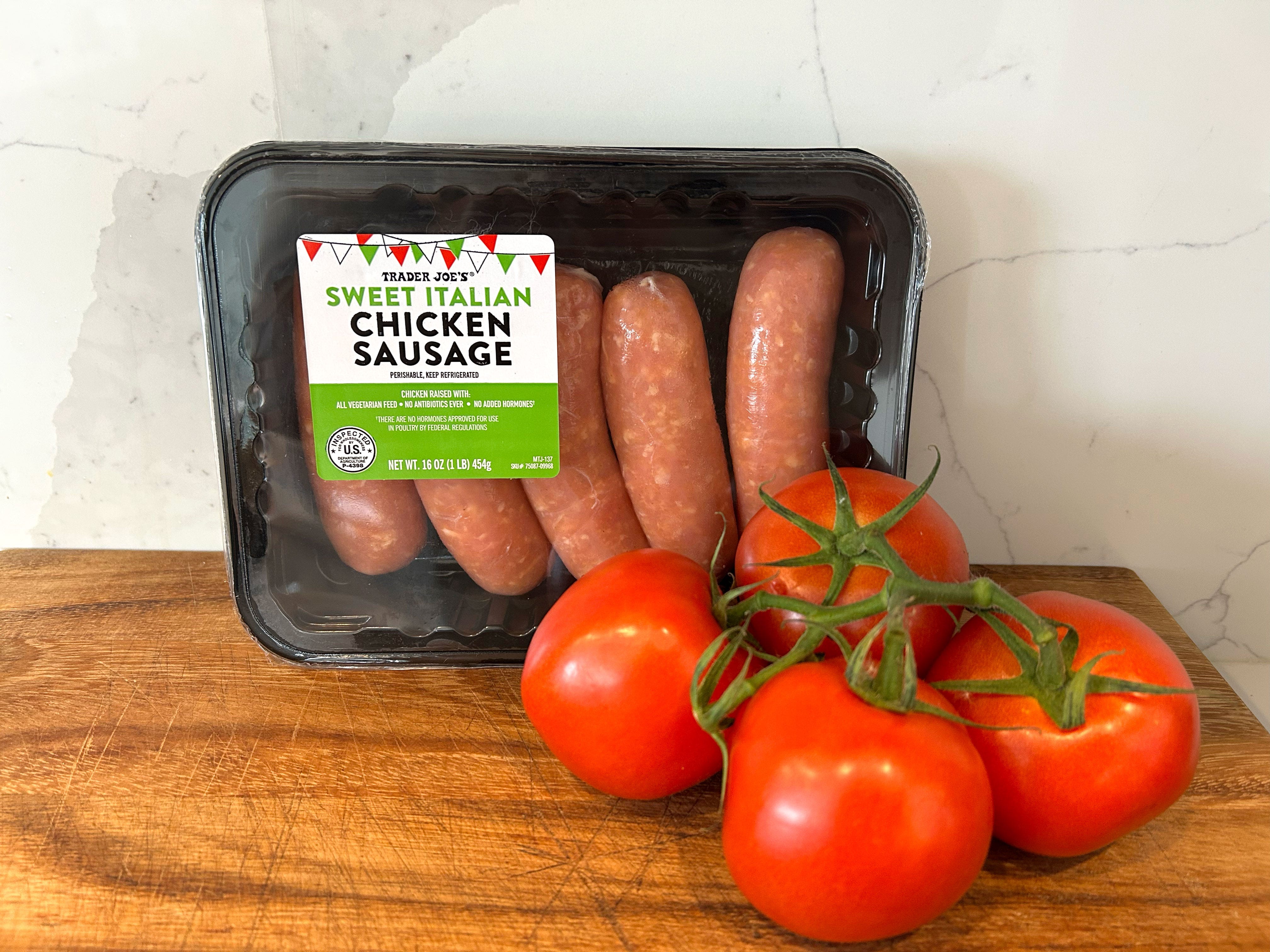 A package of Trader Joe's sweet Italian chicken sausage and some tomatoes on a cutting board.