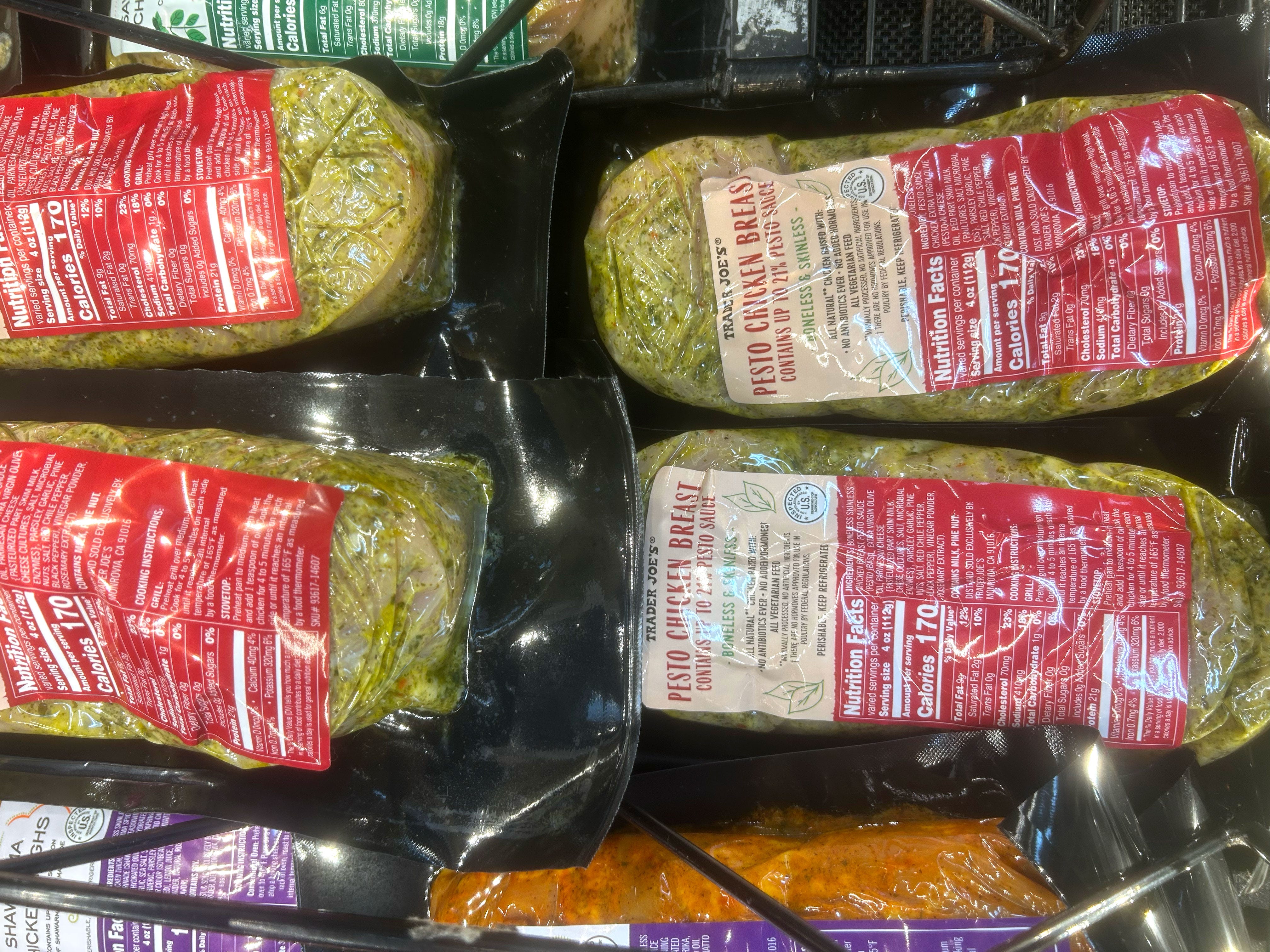 Packages of Trader Joe's pesto chicken breast in a case.