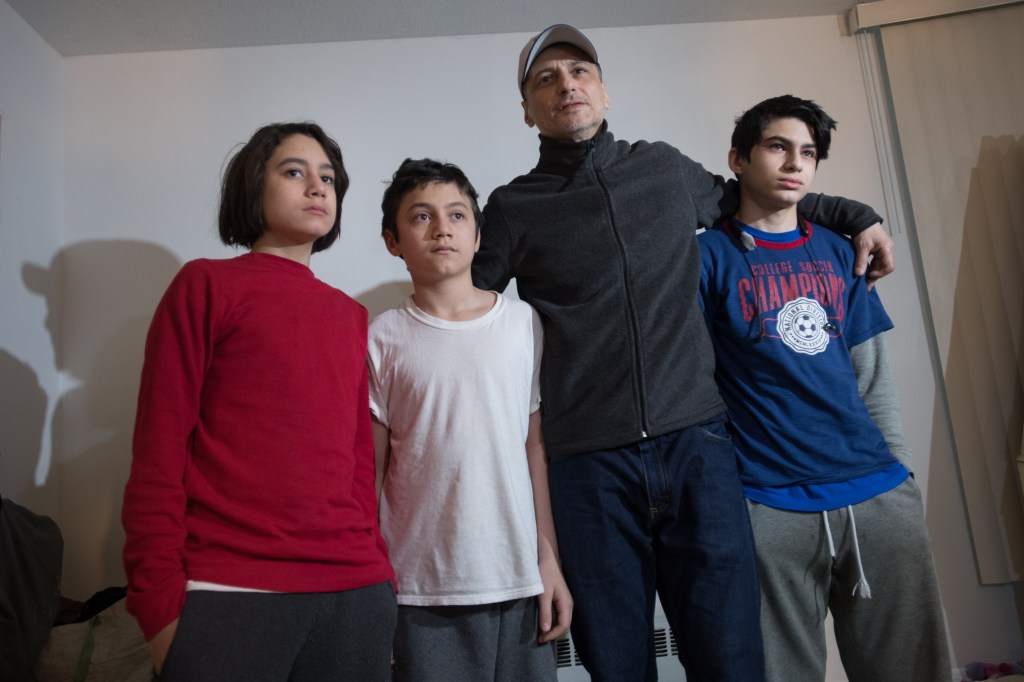 A father and his three sons posing for a photo.