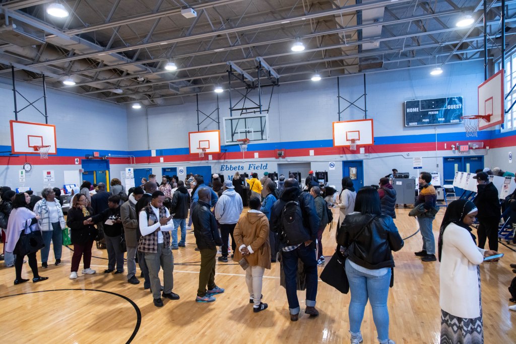 Long lines of voters at a polling place in a school gymnasium.