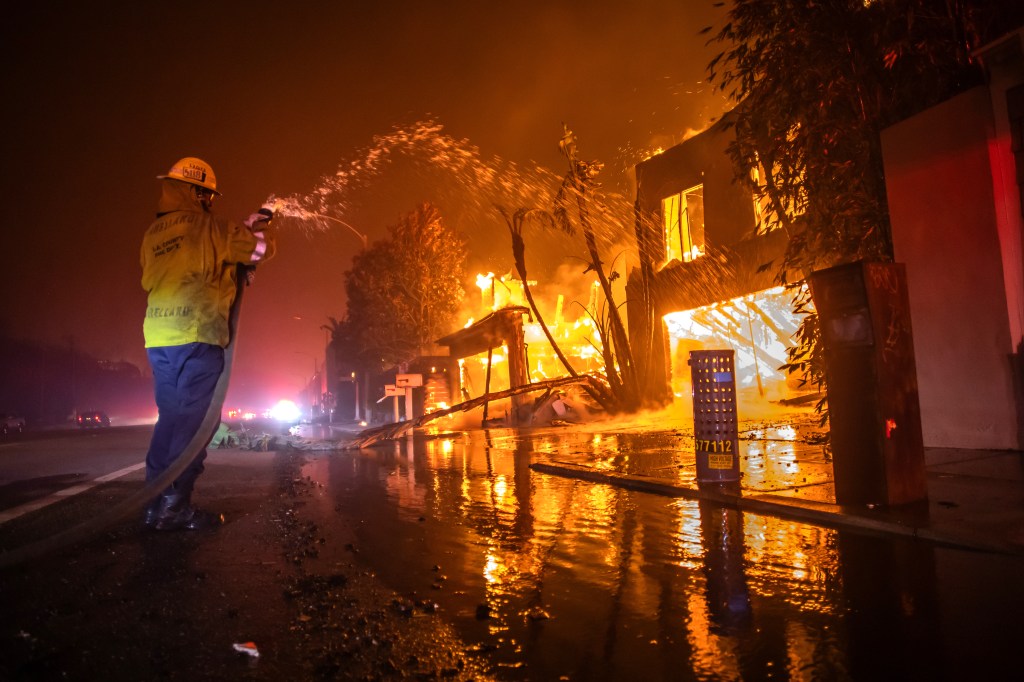 Firefighter battling a house fire at night.
