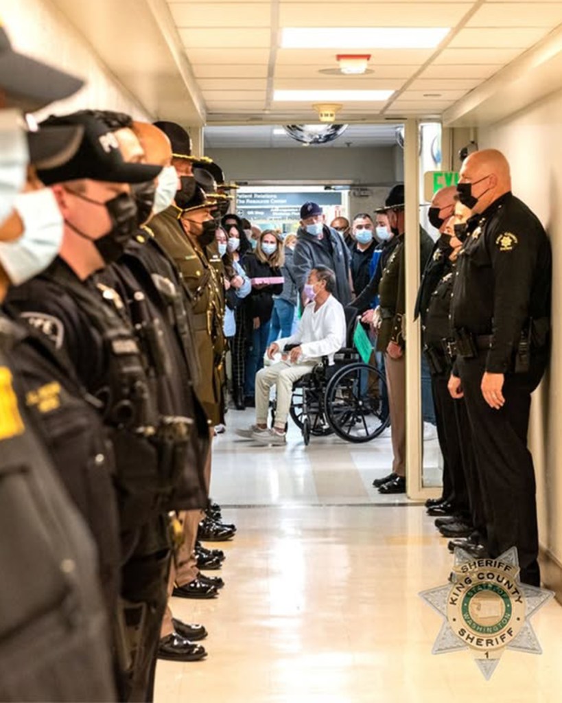 Officers lining a hallway to honor a person in a wheelchair.
