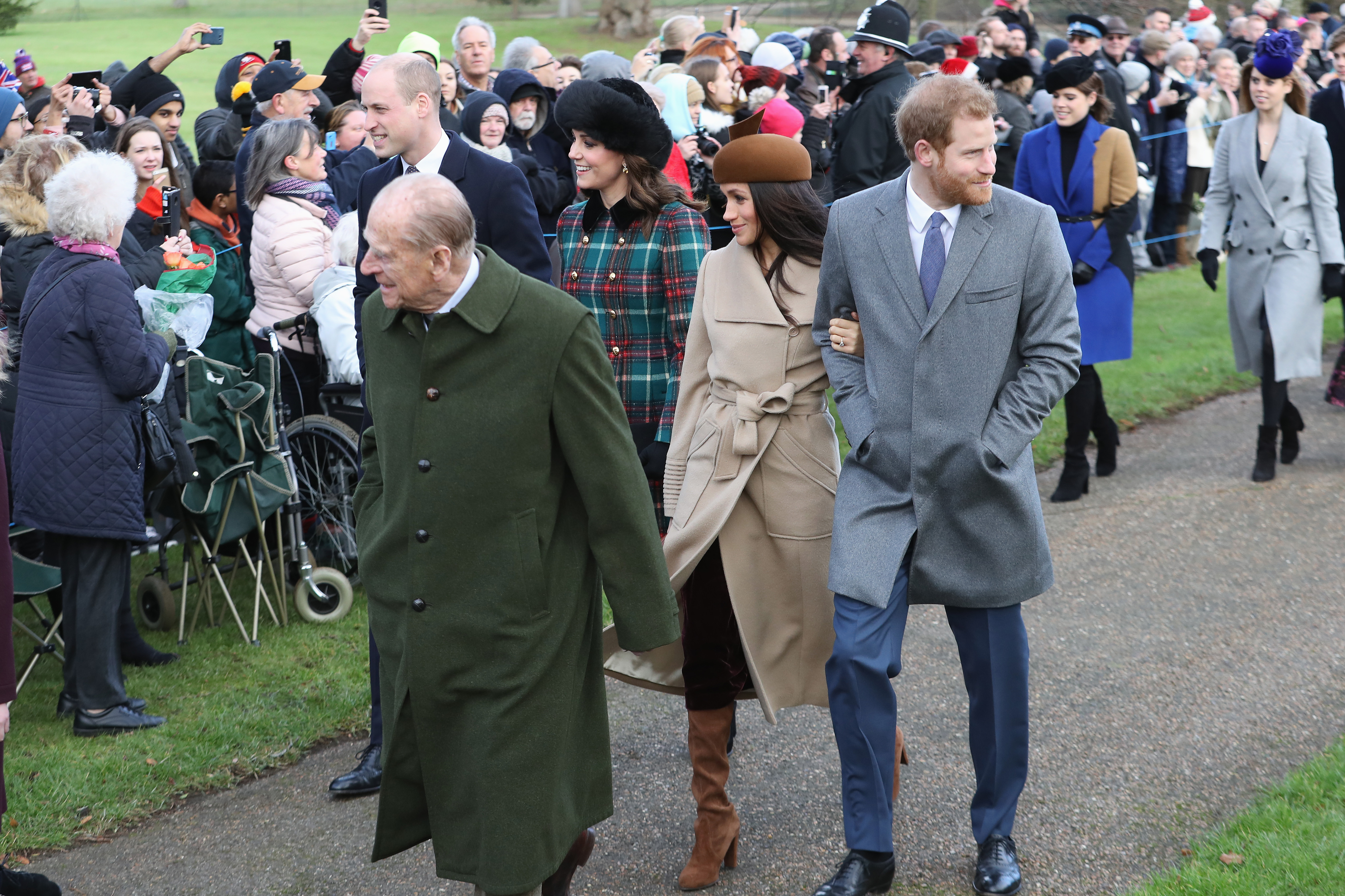Prince Philip, Meghan Markle and Prince Harry walk outdoors. 