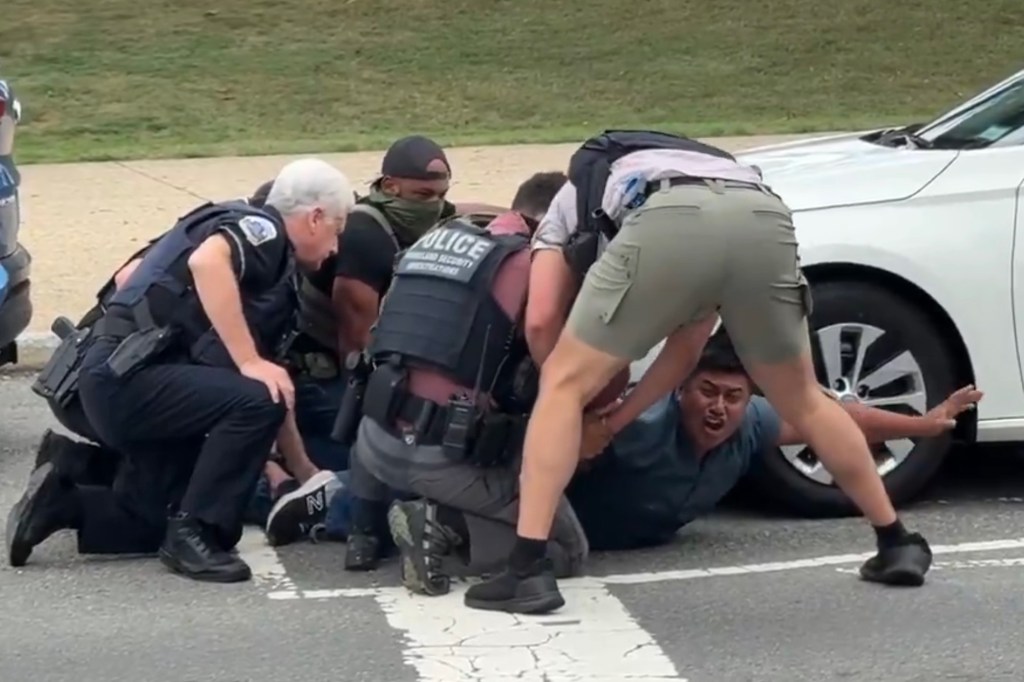 Police officers detaining a man on the ground.