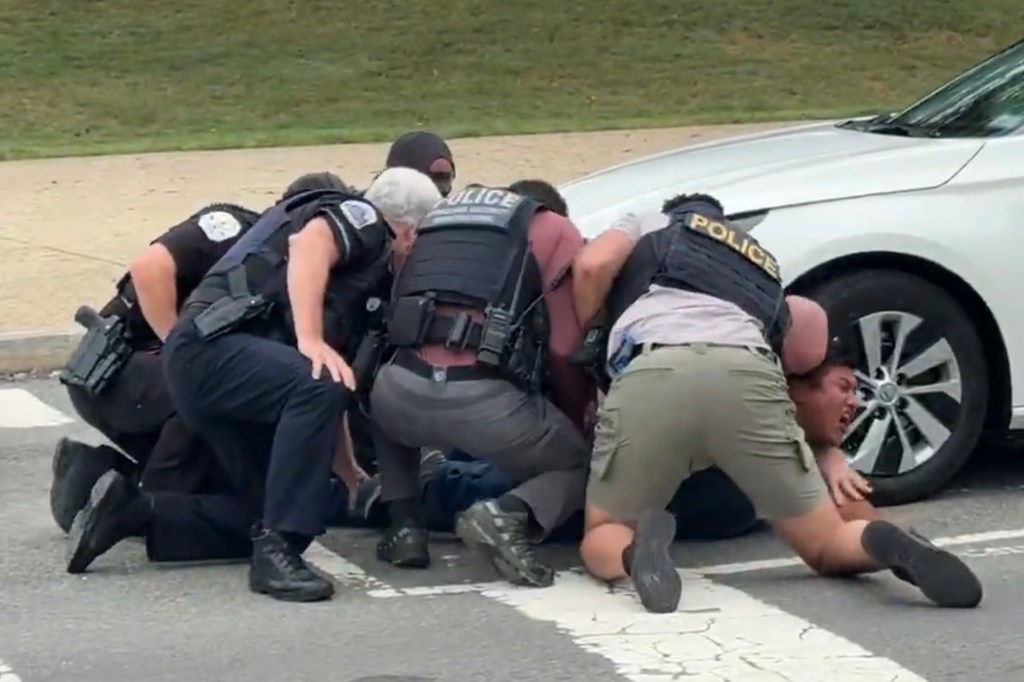 Police officers detaining a man on the ground.