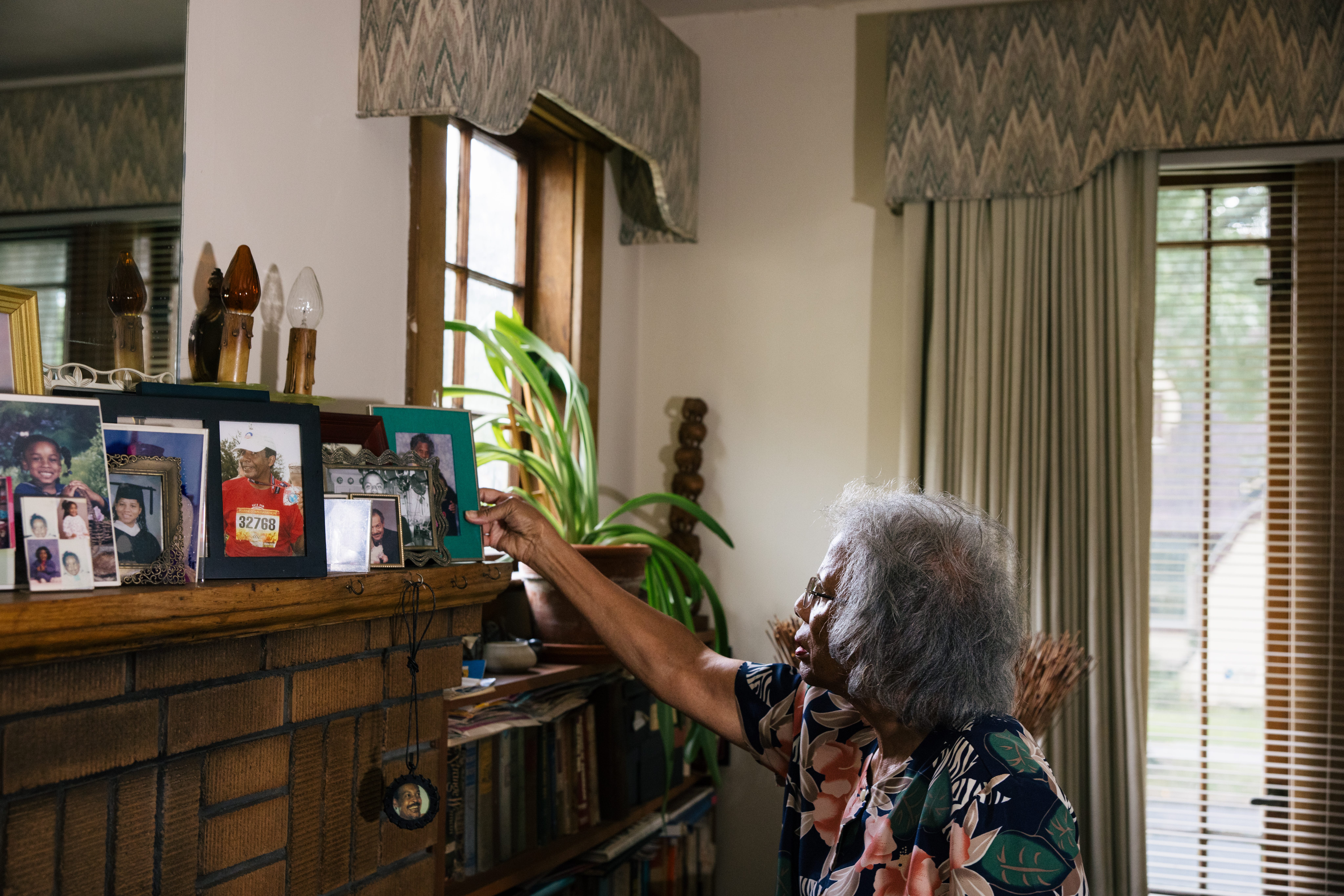 Pat is carefully organizing her collection of pictures on the chimney shelves.