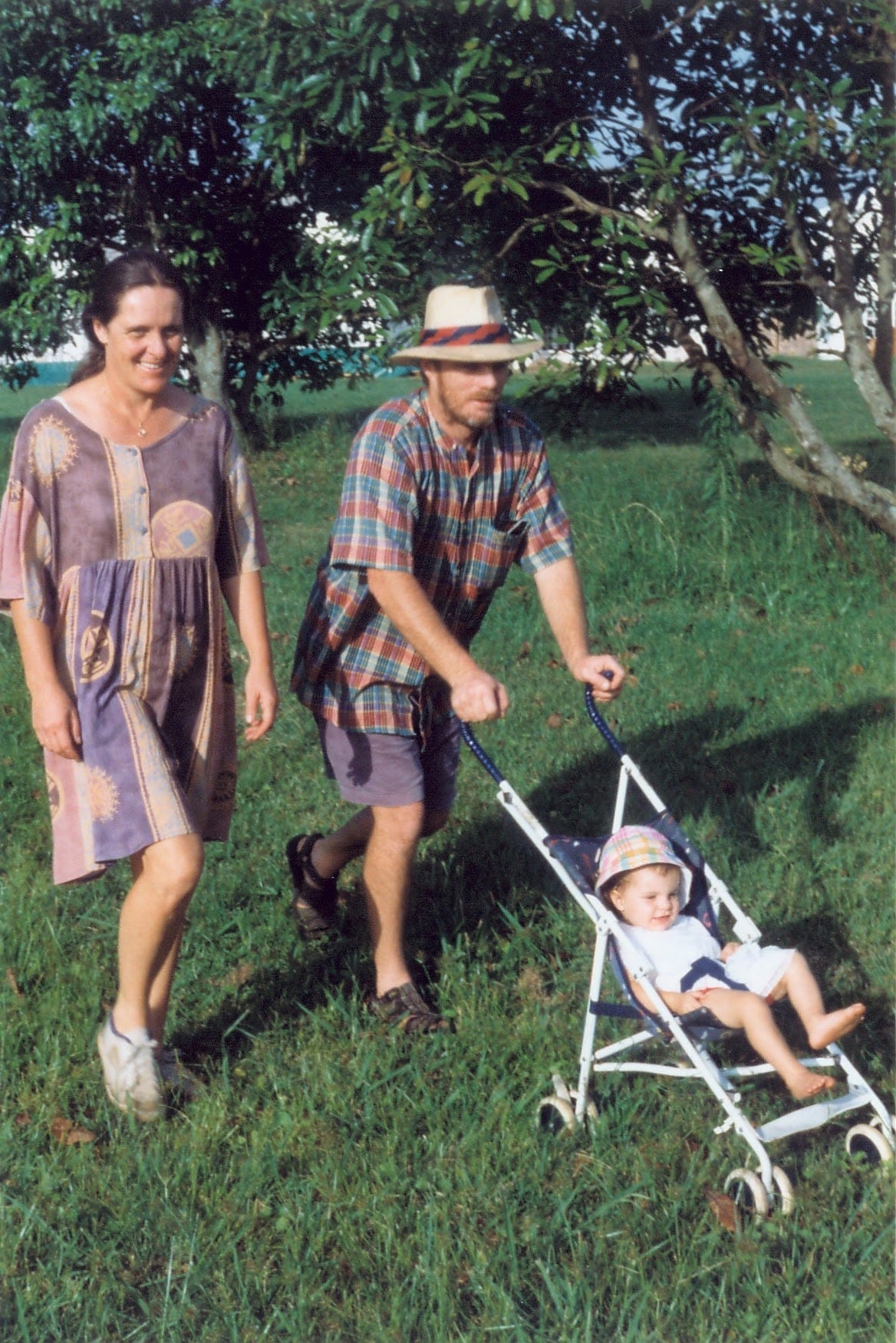 The author with her father and mother when she was young. He is pushing her on a stroller through a grassy field.