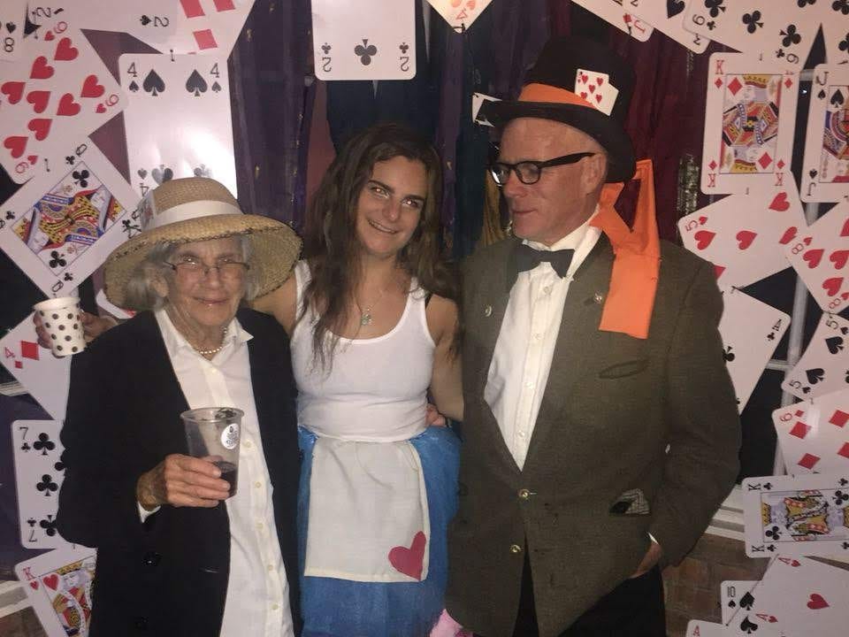 The author with her father and grandmother at her 21st birthday, dressed up in front of a backdrop of playing cards.