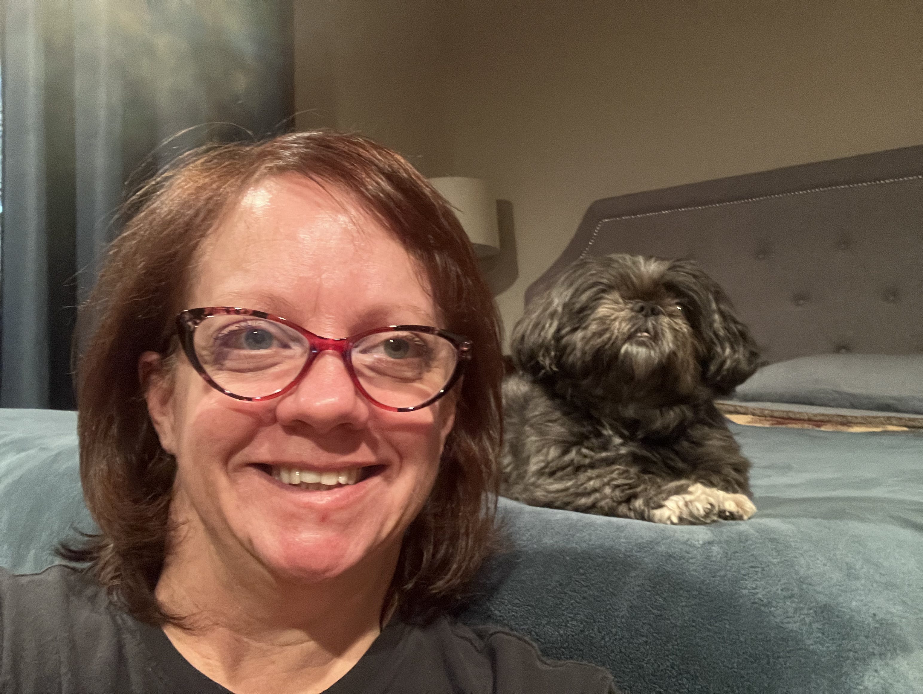 woman with dog in background on bed