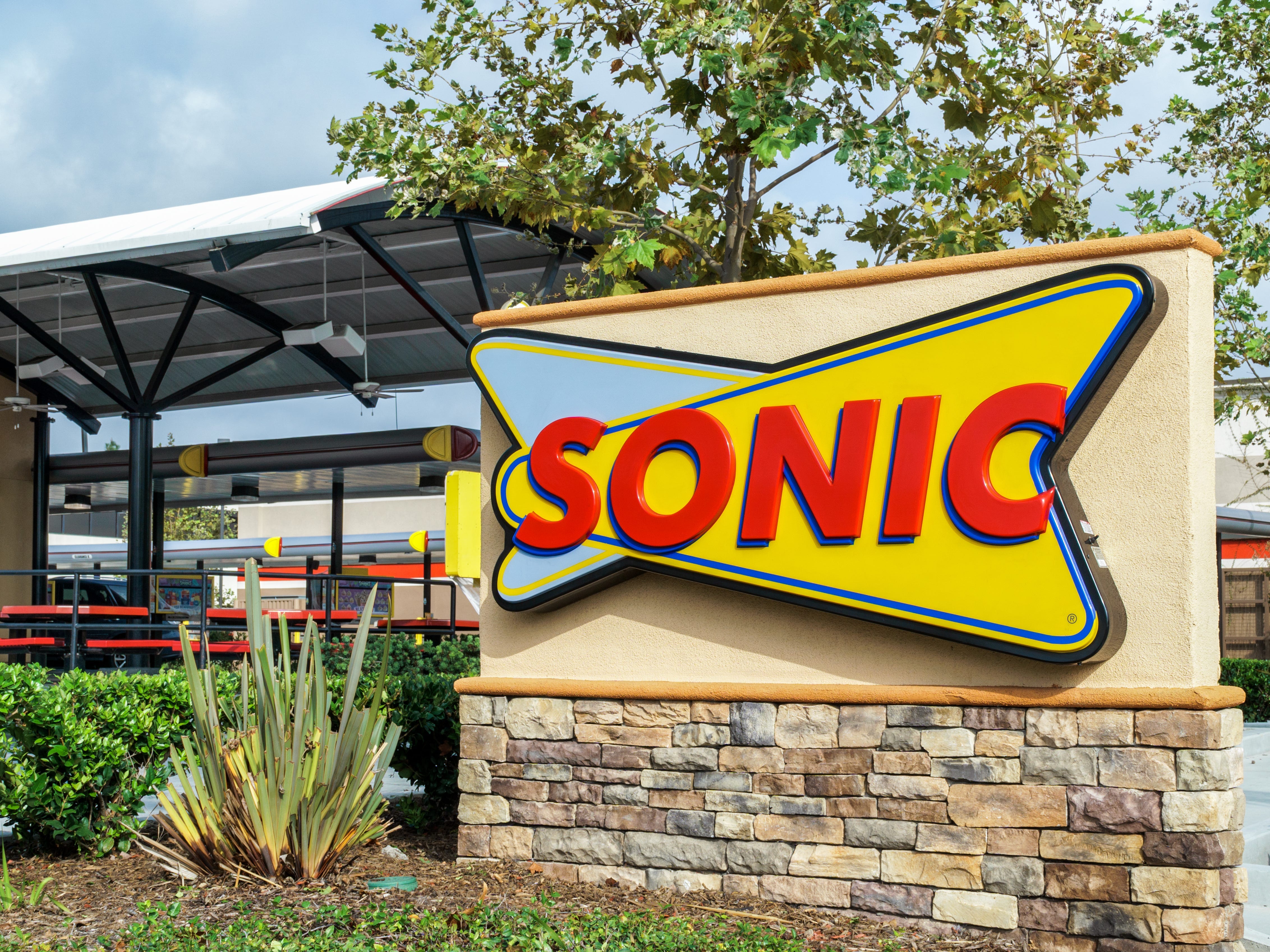 The exterior of a Sonic restaurant with it's sign in the foreground.