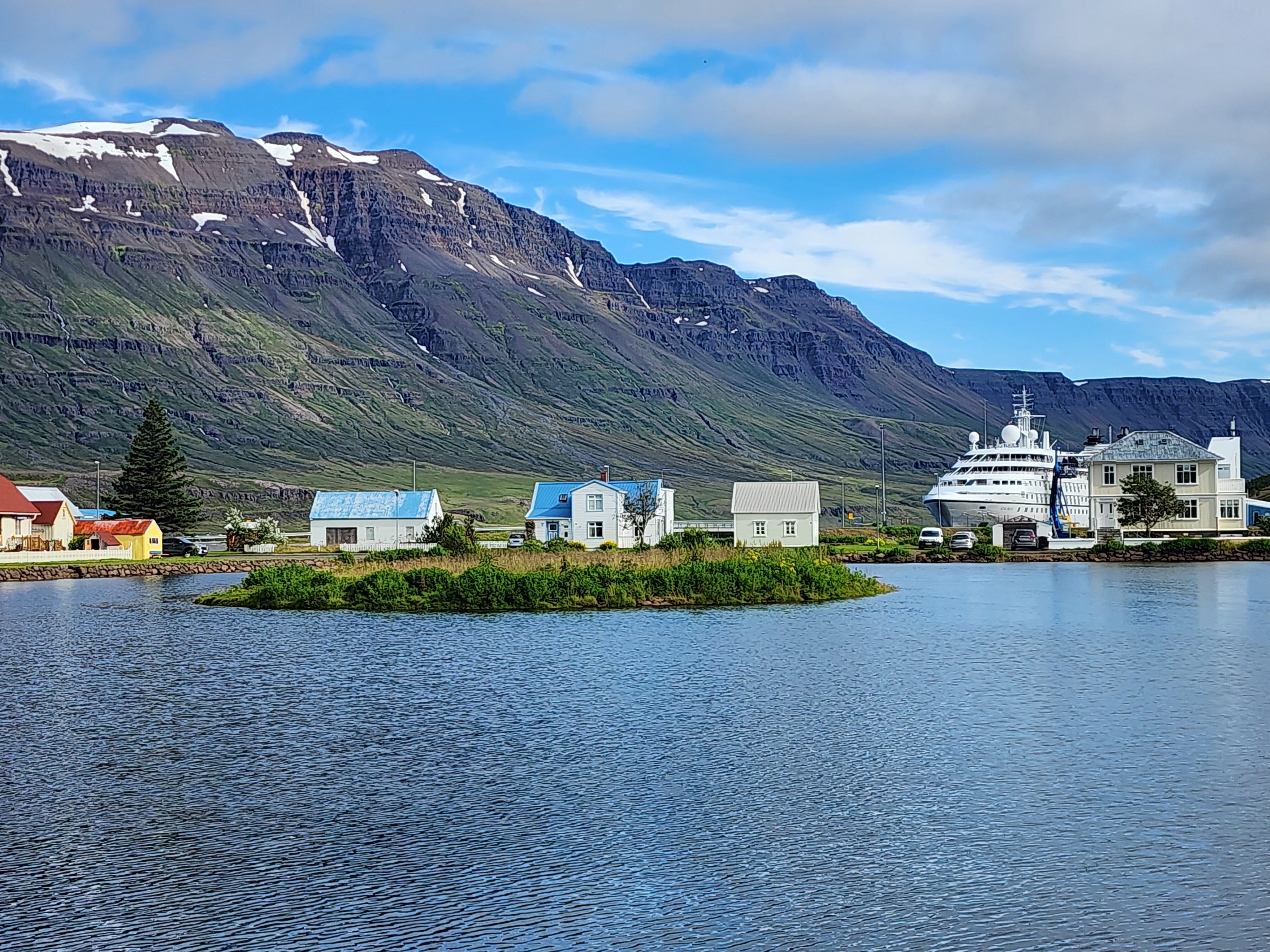 A cruise ship in an Icelandic port with mountains behind it.