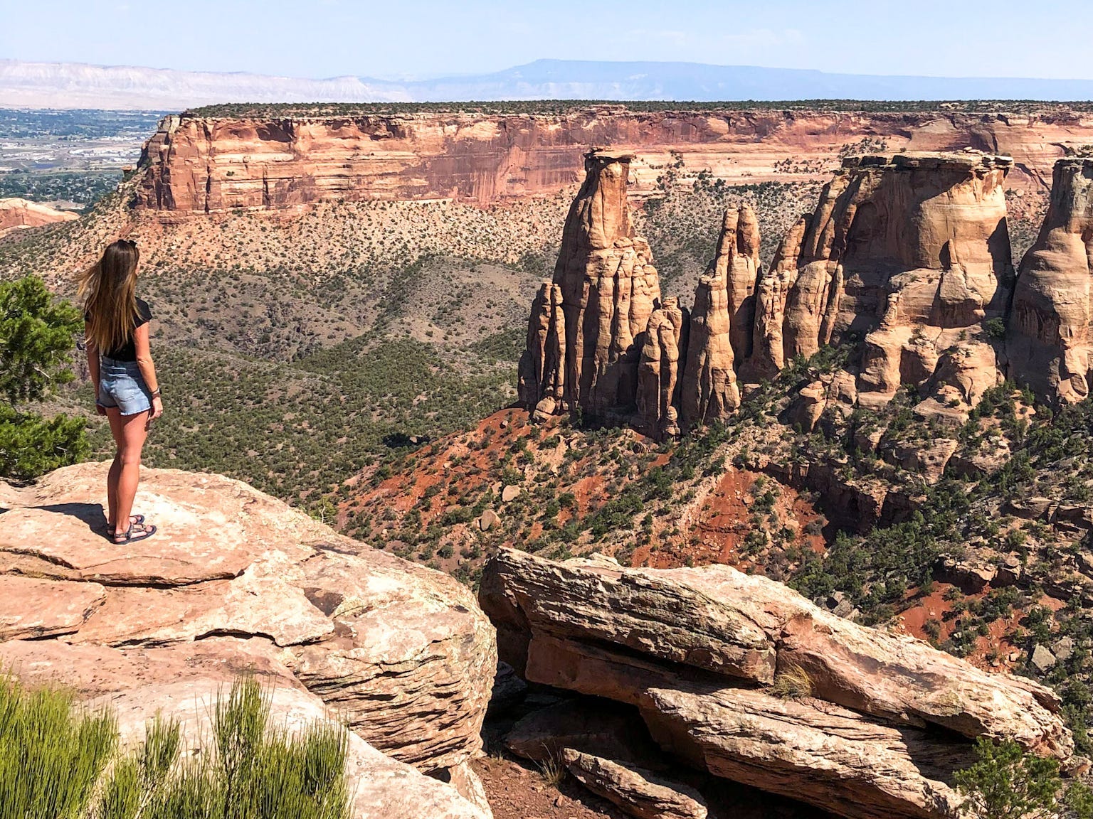 A woman standing on a rock looking out at a canyon.