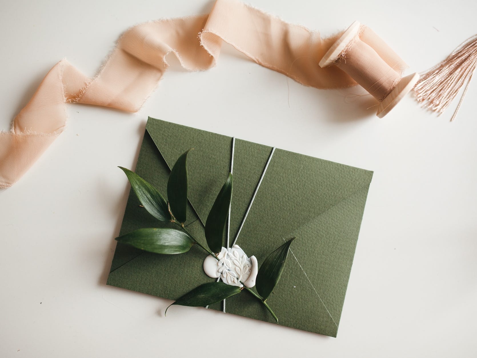 A green wedding invitation sits on a white table.