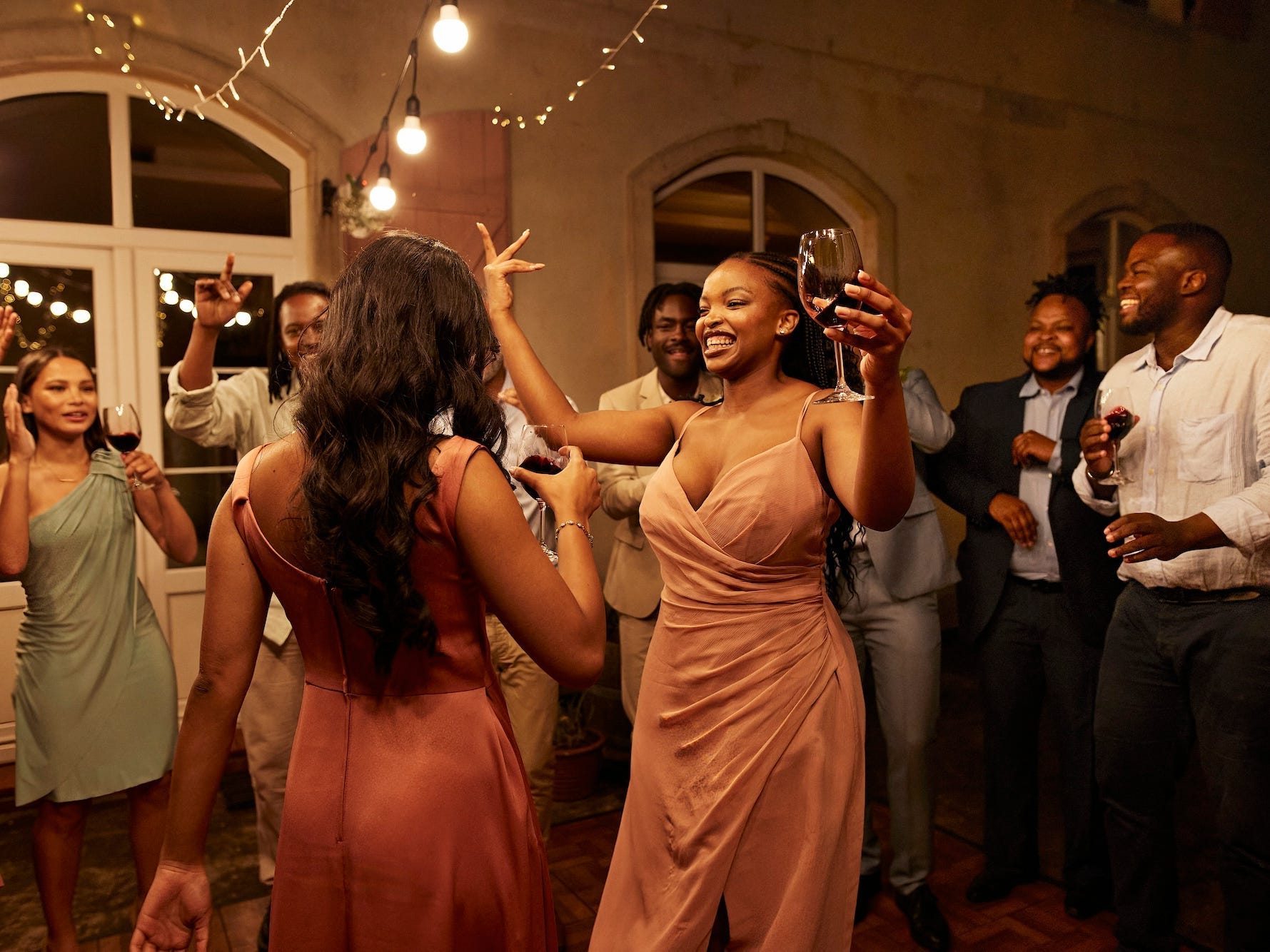 Bridesmaids dance at a wedding as guests surround them in a circle.