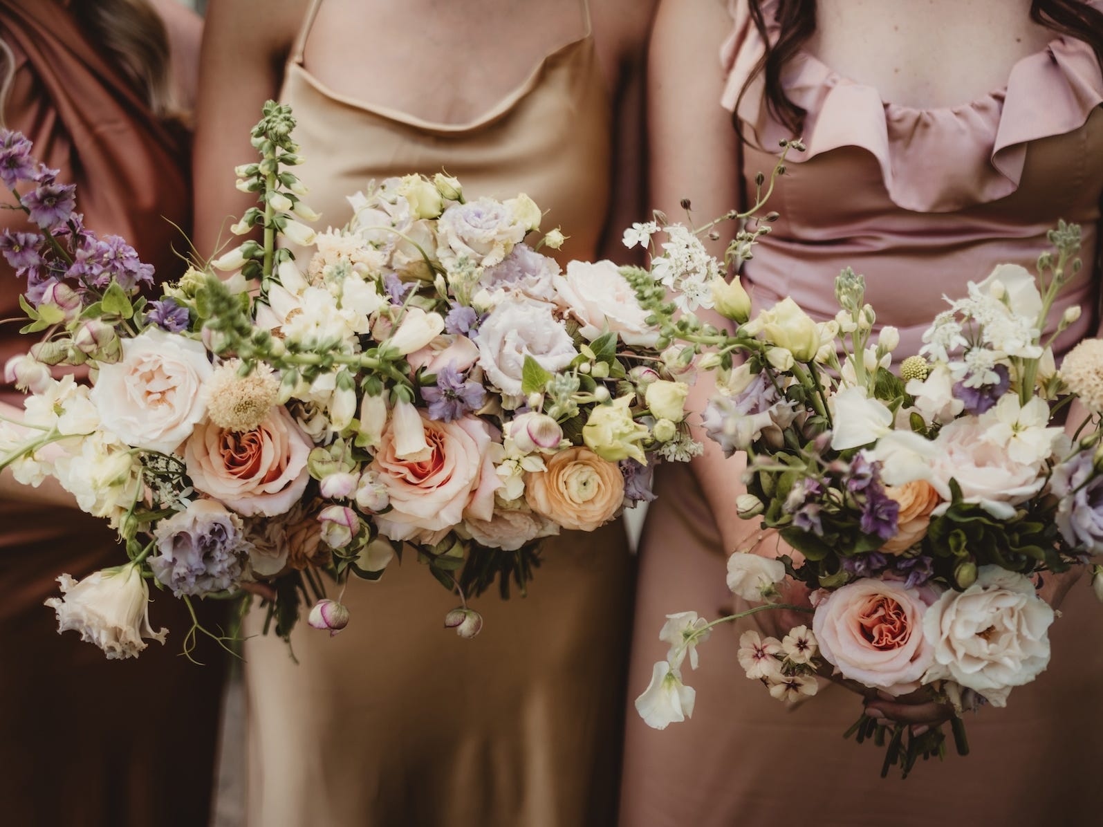 Three women hold bouquets of flowers at a wedding.