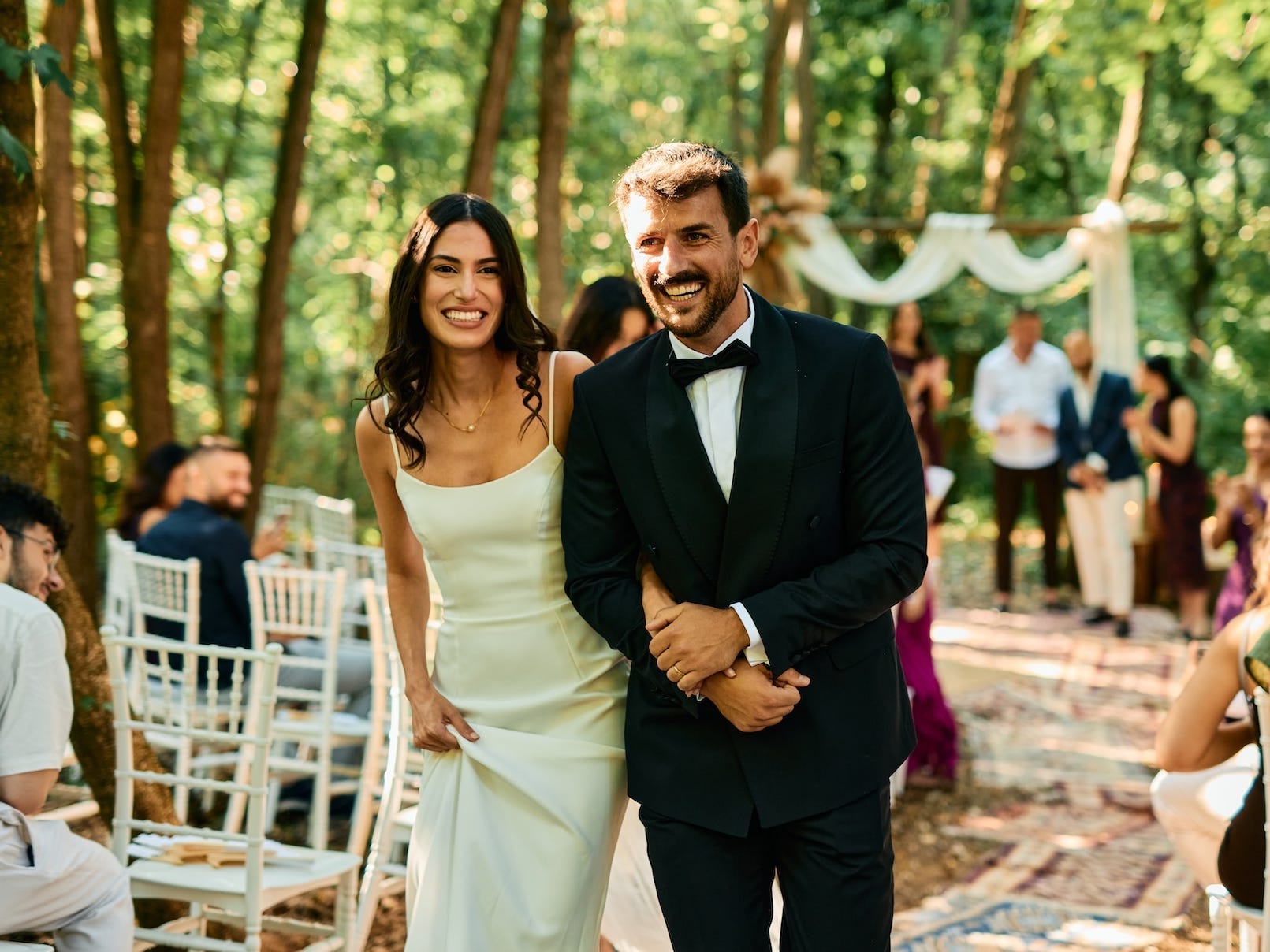 A bride and groom smile as they exit their wedding ceremony.