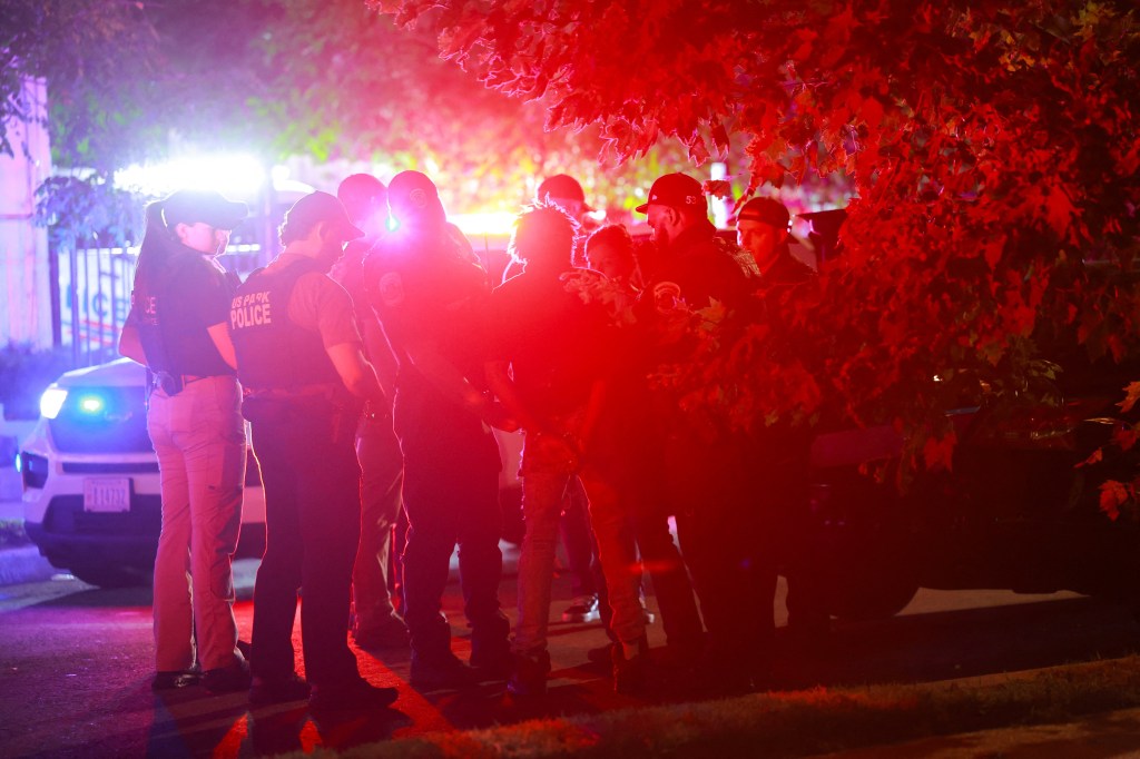 Police officers detaining a man at night.