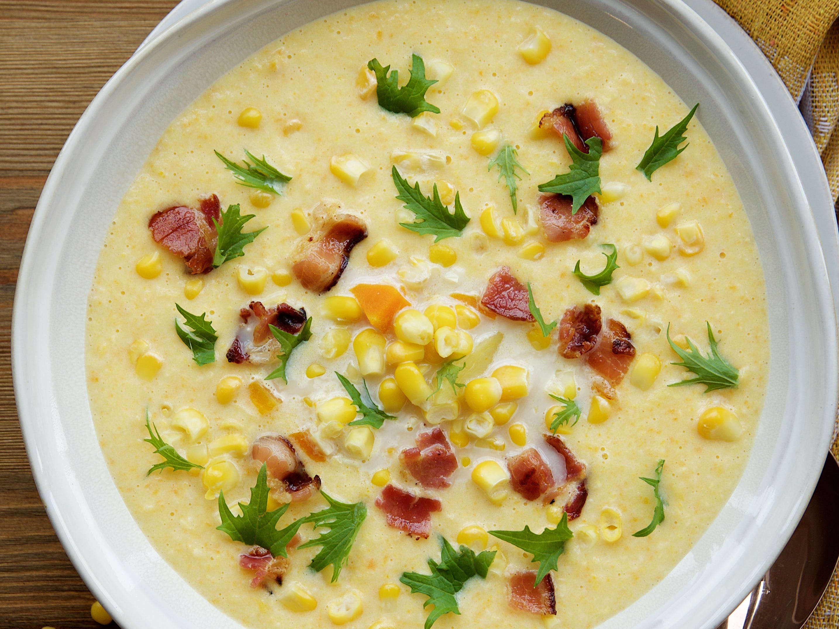 corn chowder with bacon on wooden background with spoon