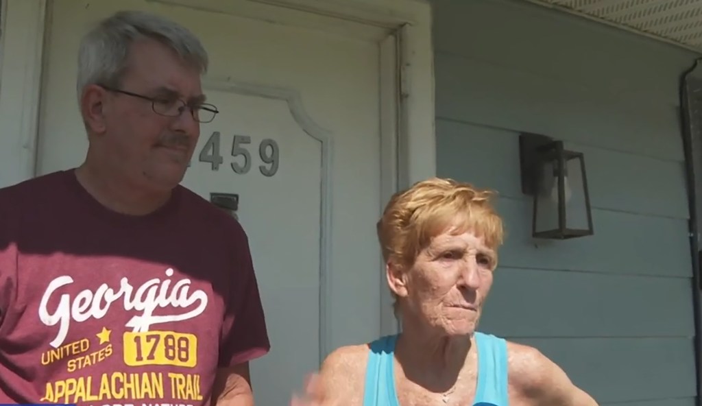 Older man and woman standing on their porch.