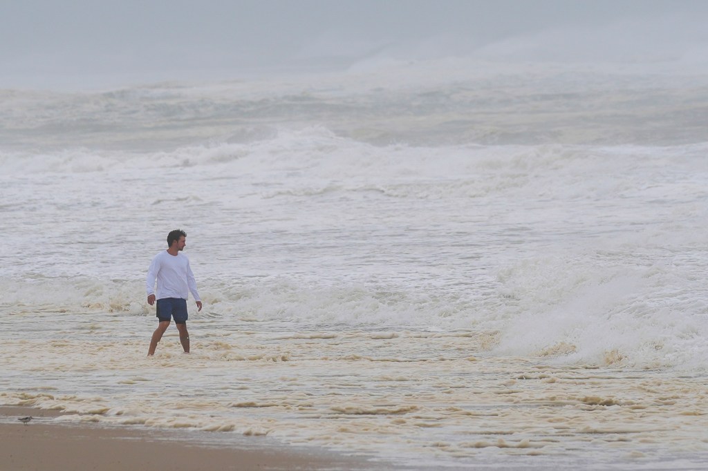 A person watches as waves from Hurricane Erin crash along beach in Duck, N.C., on Thursday, Aug. 21, 2025.