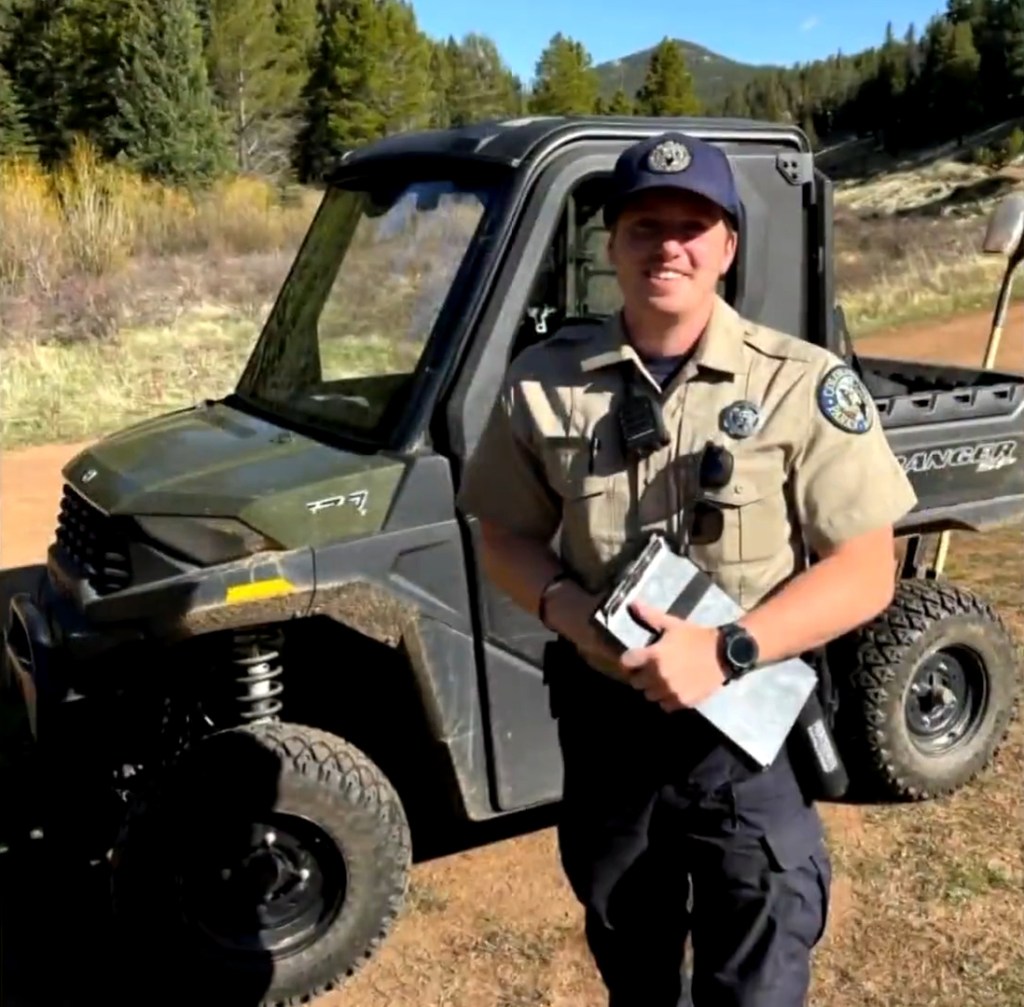 Park ranger Callum Heskett standing next to a utility vehicle.