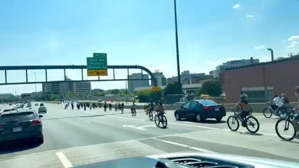 Large group of cyclists riding on a highway.