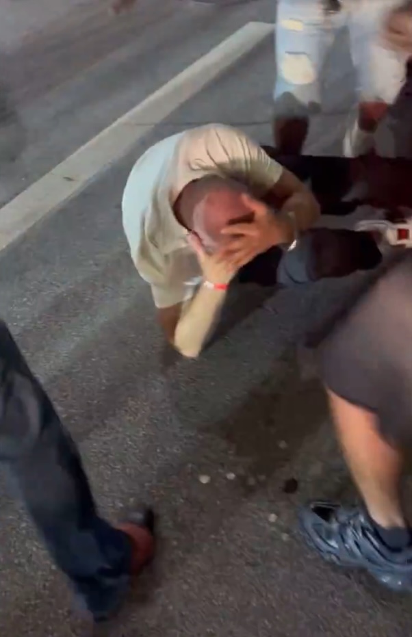 A victim holds his head on the street after being attacked during a brawl in downtown Cincinnati on July 26, 2025.