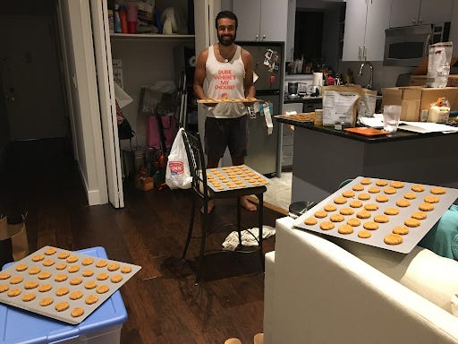 Krishna Kaliannan smiles and holds a tray of baked cereal in his kitchen
