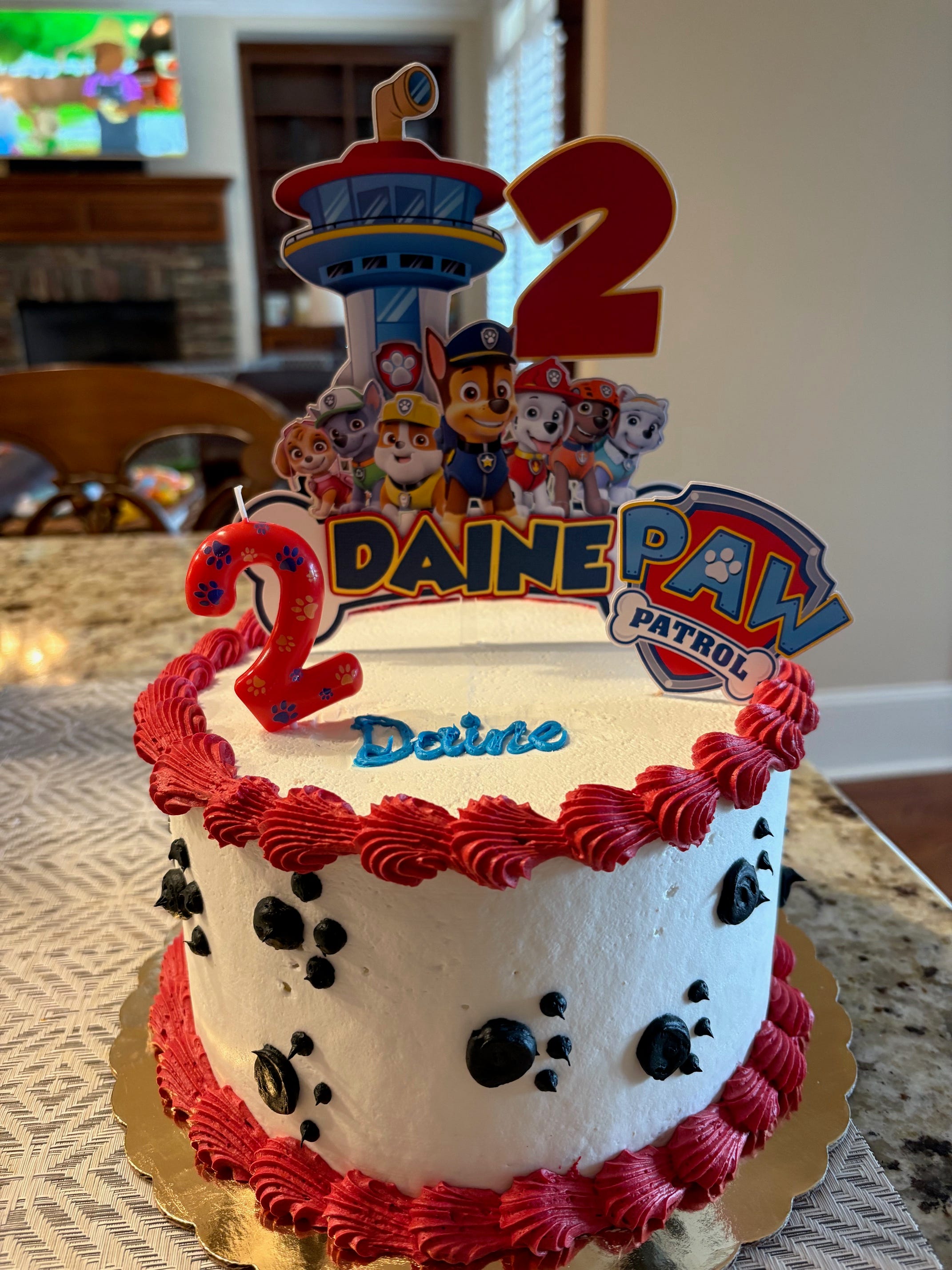 A red and white cake with a Paw Patrol cake topper.