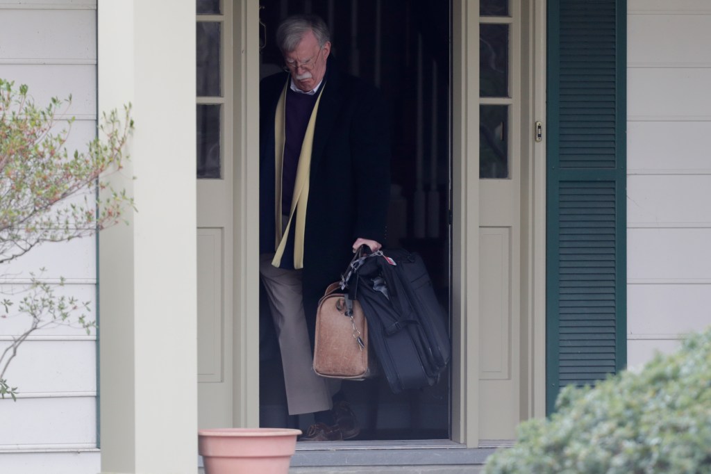 John Bolton leaving his home with luggage.