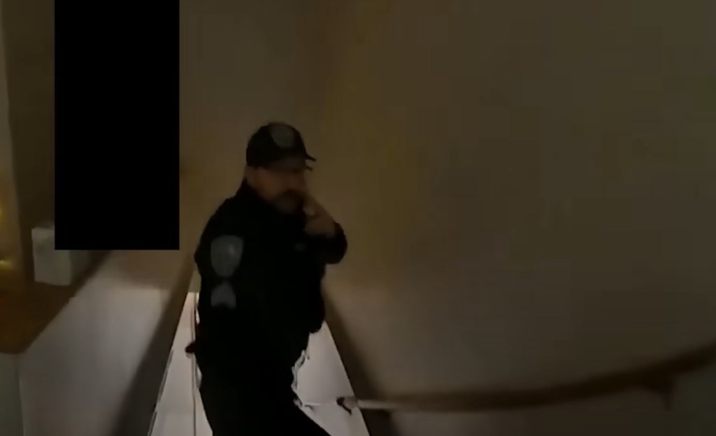 A police officer ascends a staircase inside the home where at least two of the college students were discovered.
