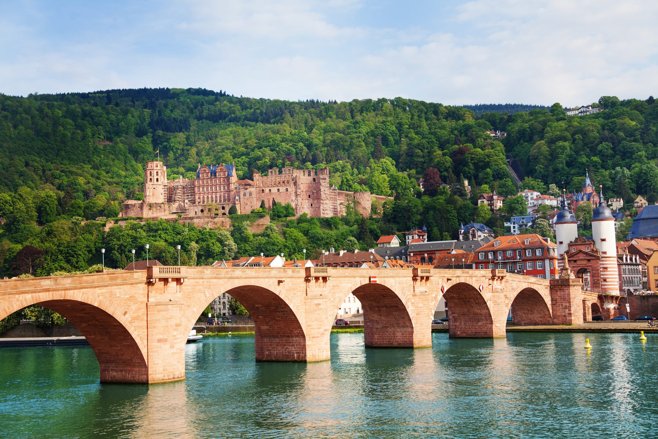 A bridge over a river, with buildings and a castle in the background.