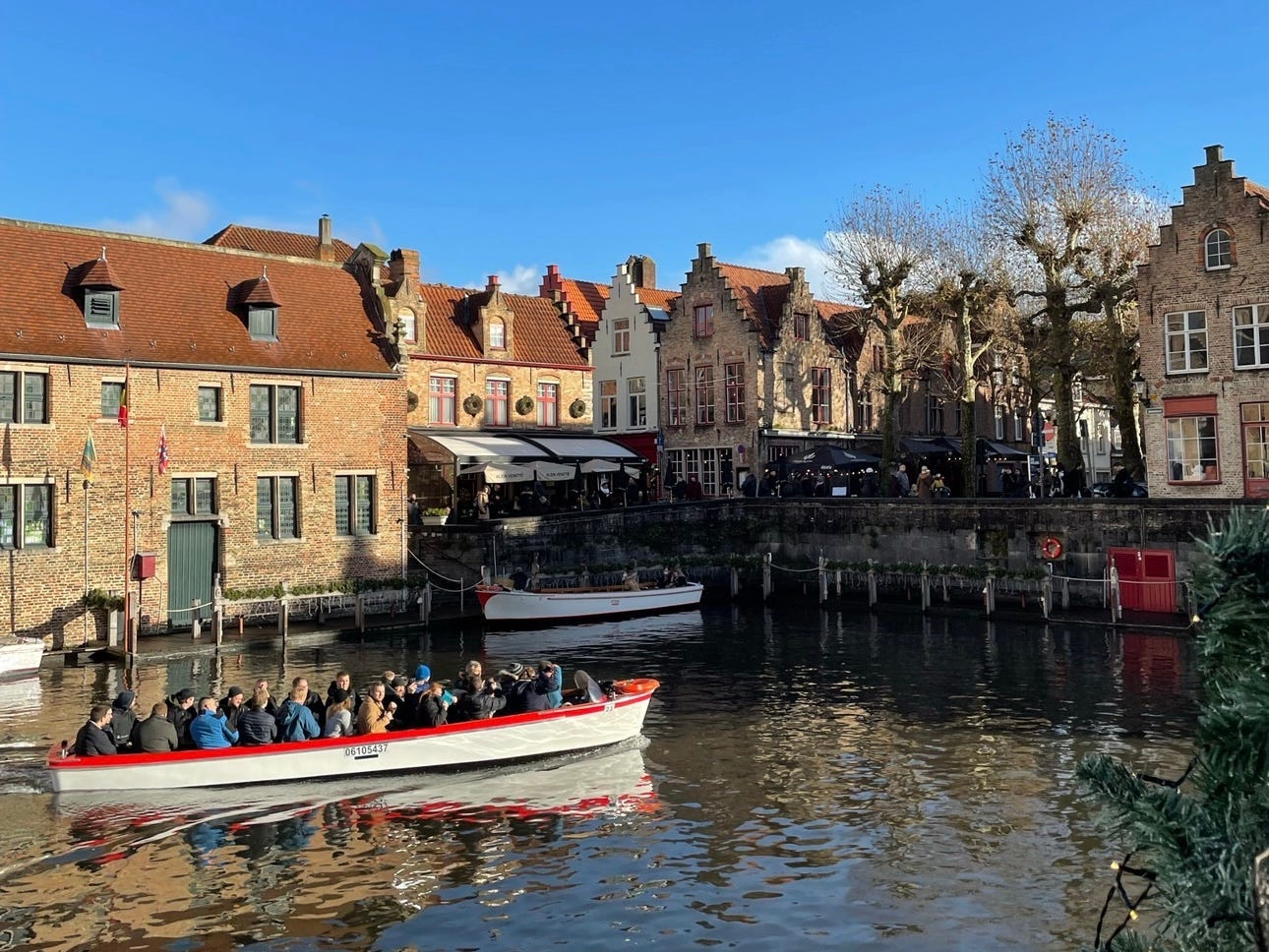 People riding in a boat on a river surrounded by charming brick buildings.