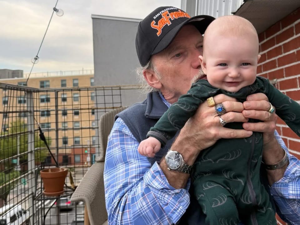 Steve kisses his grandson while holding him up.