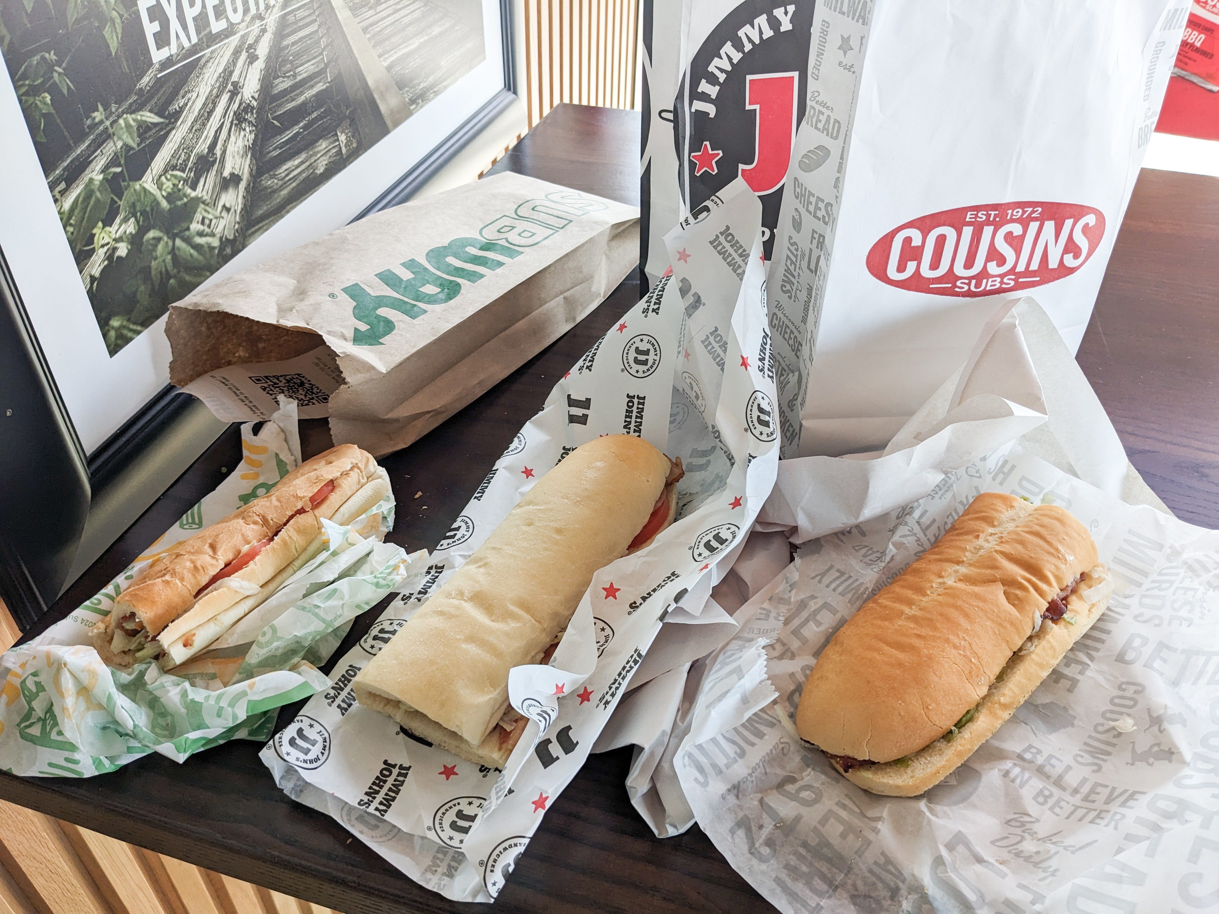 The author's BLTs from Subway, Jimmy John's, and Cousins Subs are displayed next to each other unwrapped.