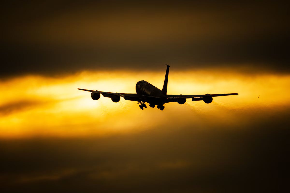 A US Air Force KC-135 Stratotanker aircraft flies into a sunset.