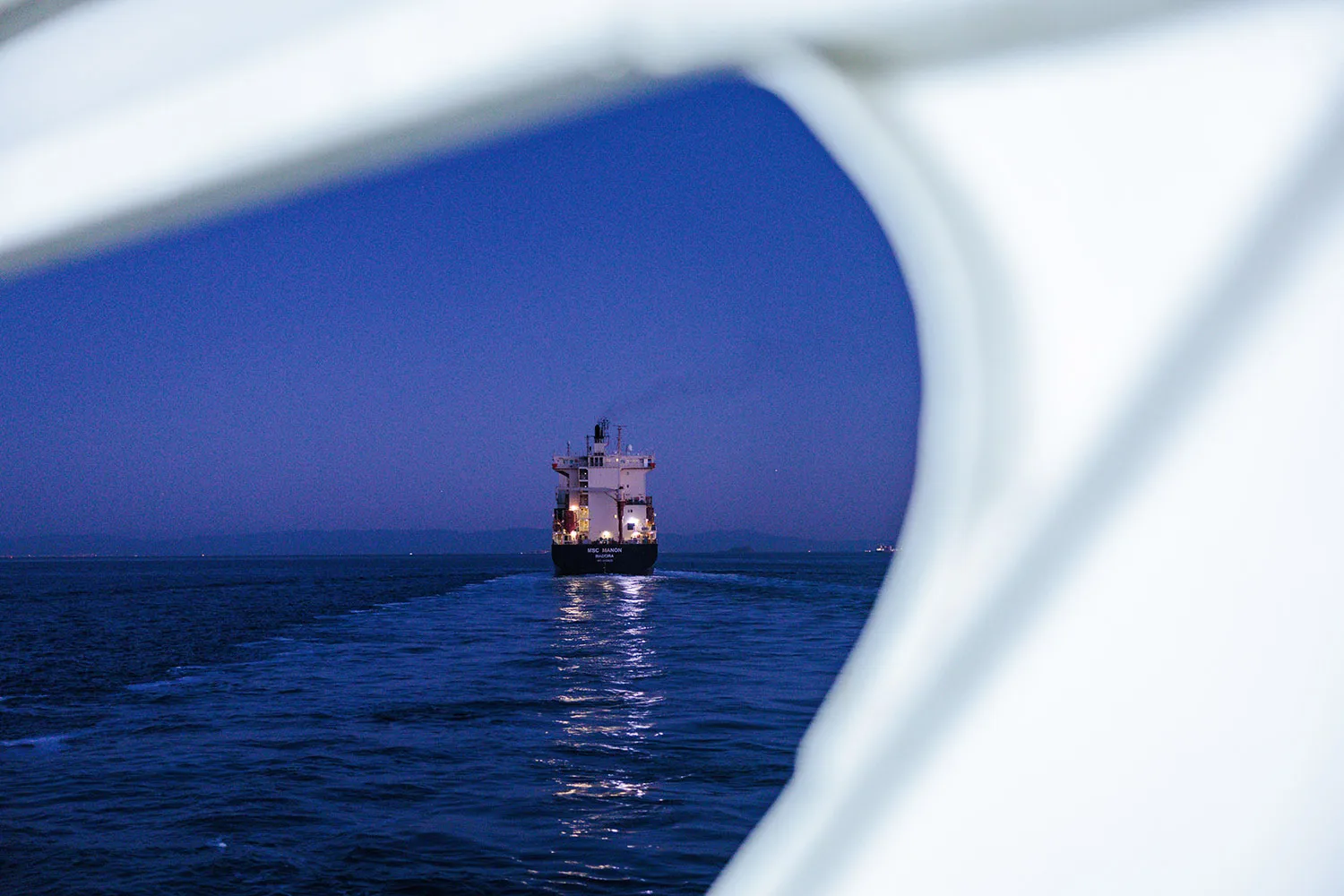 A ship is seen through an opening on a nighttime sea.