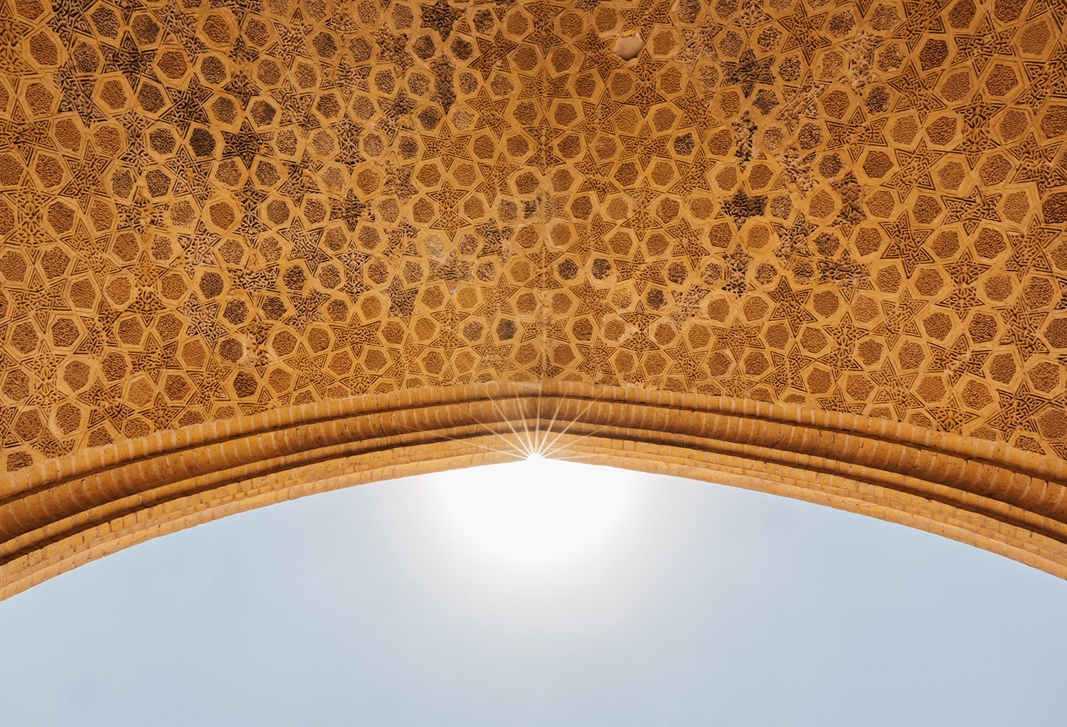 The sun glints at the center of ornate tiled archway