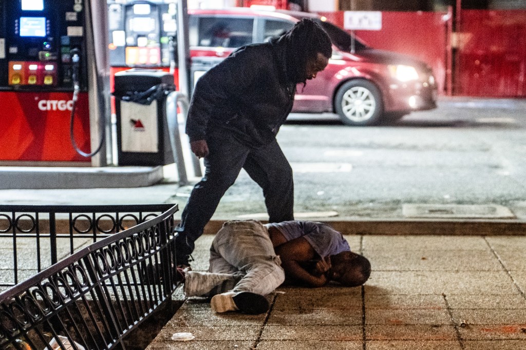 A man stands over another man on a street during a physical altercation in Washington, DC, on Aug. 21, 2025.