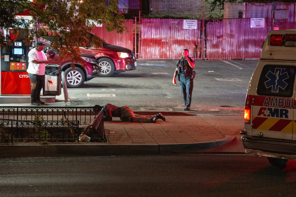 A Washington Metropolitan Police officer walks over to the a man injured in a physical altercation on the streets of Washington, DC, on Aug. 21, 2025. 
