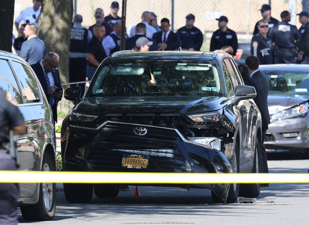 Damaged black Toyota SUV at a crime scene; NYPD officers present.