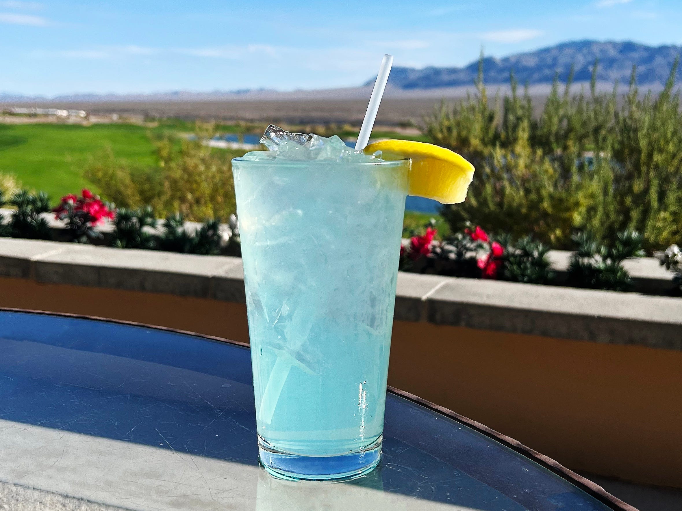 A blue drink with a golf course and mountains in the background.