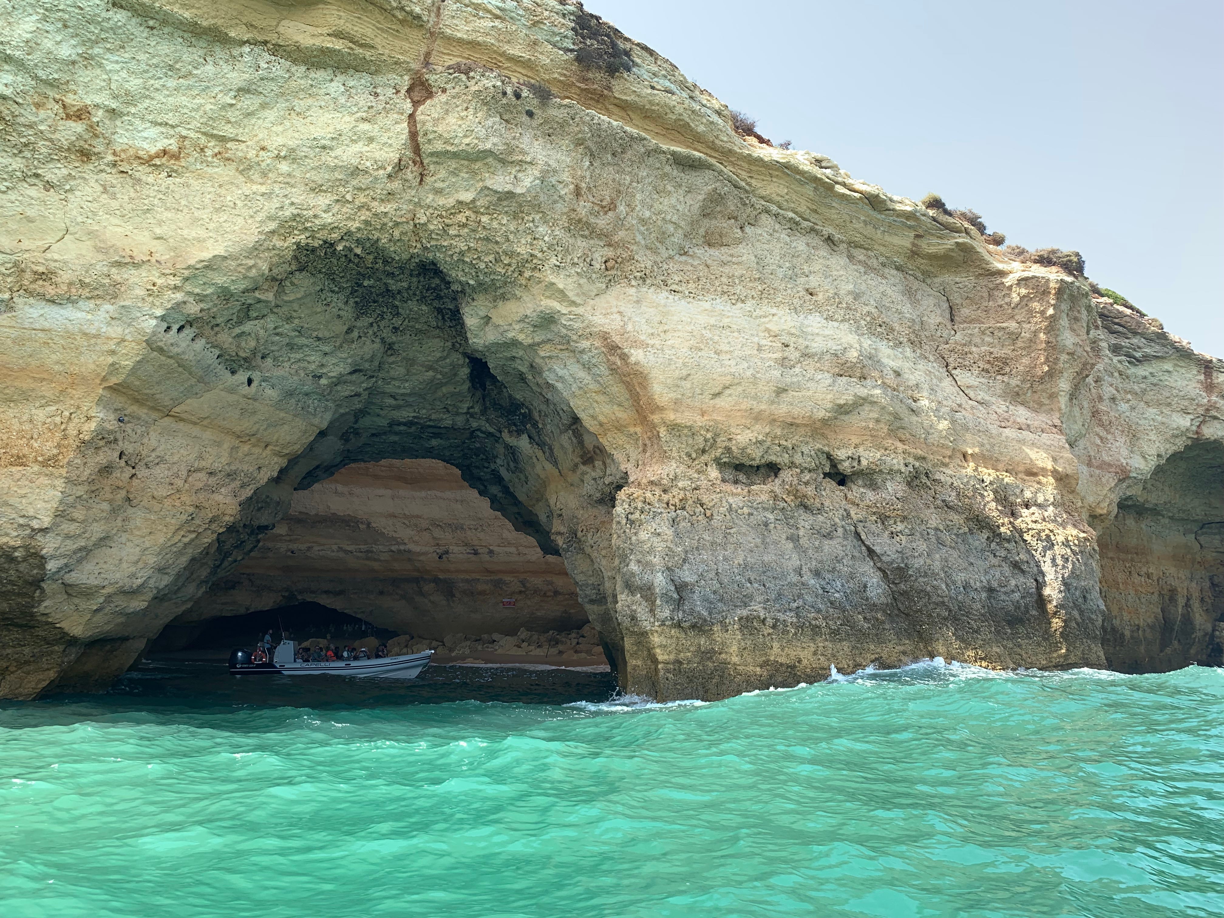 The author's view from the water looking at a cave in Puglia, Italy. There's a boat with people inside the cave.