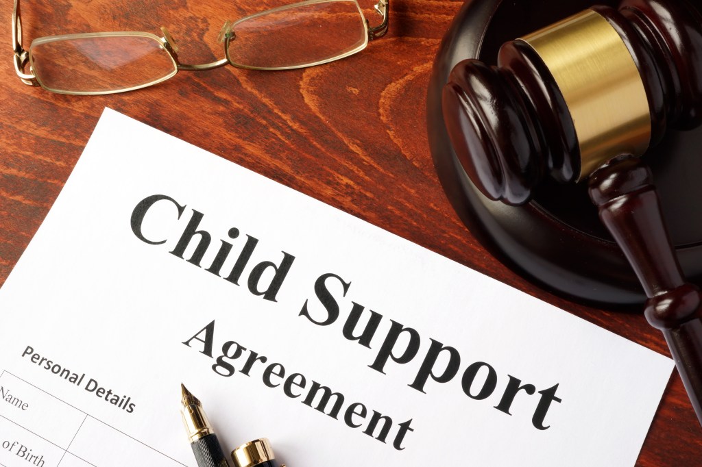 Child support agreement on a desk with a gavel and glasses.