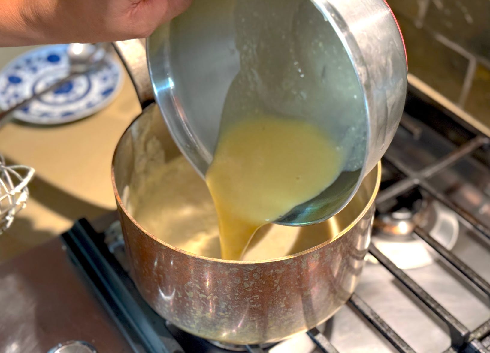 Pouring a tempered egg into a roux.