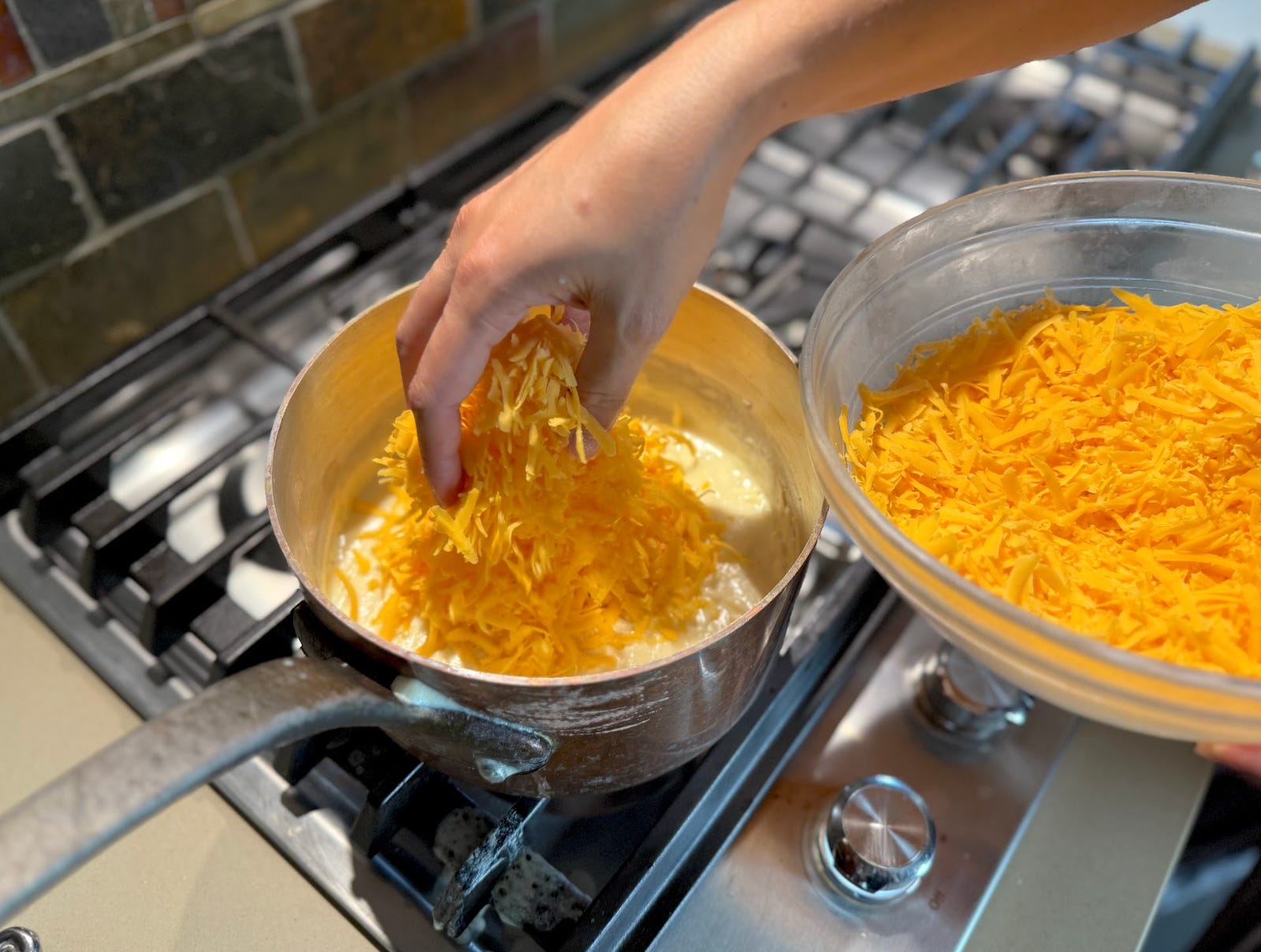 Adding cheddar to the sauce on the stovetop.