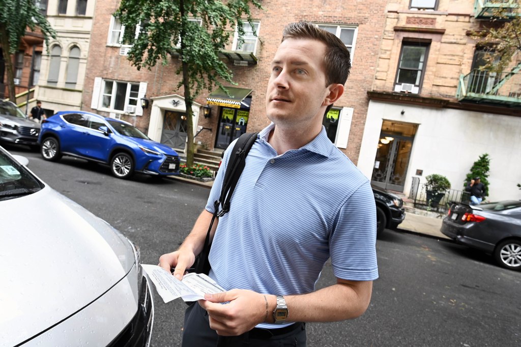 Sam Johnson holding a parking ticket in front of his rental car on West 73rd Street on Aug. 21, 2025