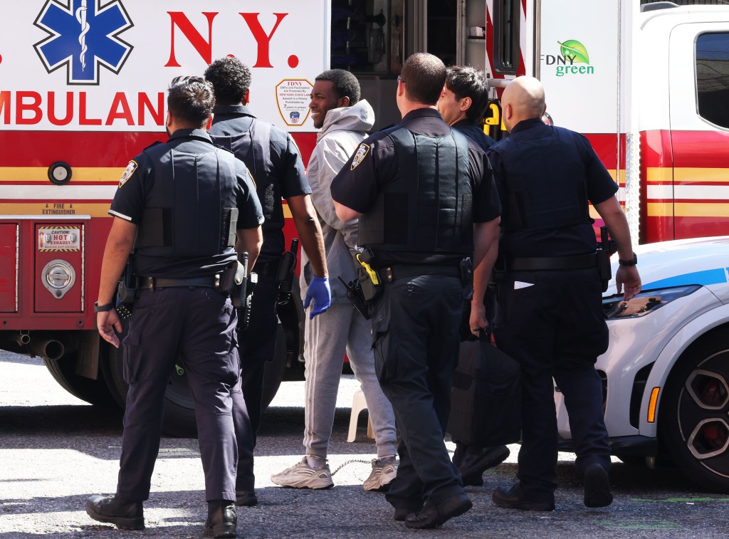 Kevin Dubuisson surrounded by NYPD officers in front of an ambulance at the 109th Precinct on Aug. 23, 2025